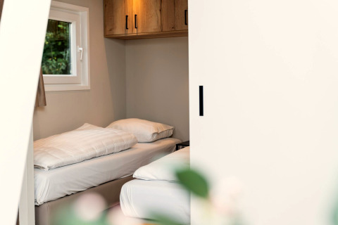 Knusse kamer bij Berg Lodge in Nederland met twee eenpersoonsbedden, een raam en houten kasten.