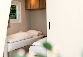 Knusse kamer bij Berg Lodge in Nederland met twee eenpersoonsbedden, een raam en houten kasten.