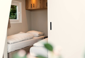 Cozy room at Berg Lodge in the Netherlands with two single beds, a window, and wooden cabinets.