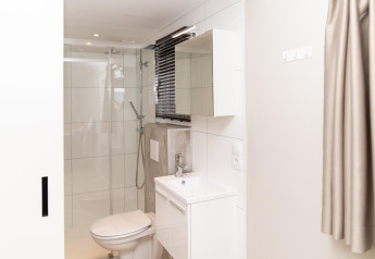 Contemporary bathroom at Berg Lodge in the Netherlands featuring a shower, toilet, sink, and mirror.