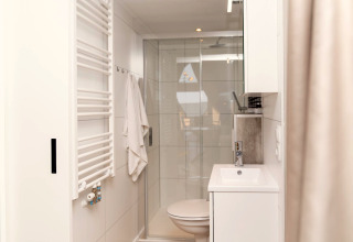 Moderne, lichte badkamer in Berg Lodge, Nederland met douche, handdoek en wit interieur.