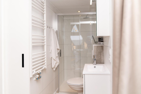 Moderne, lyst badeværelse på Berg Lodge i Holland med brusekabine, håndklæde og hvidt interiør.