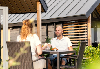 Deux personnes prennent un petit-déjeuner paisible en terrasse à la Berg Lodge aux Pays-Bas.