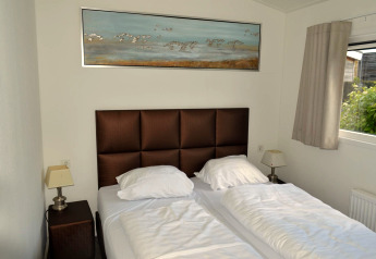 Slaapkamer in 'Biebosch' Sunshower Lodge in Nederland met twee eenpersoonsbedden en een schilderij aan de muur.