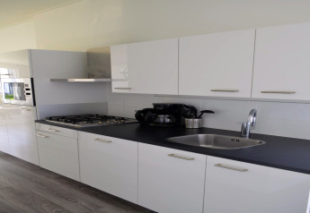 Moderne keuken in lodge 'Biebosch' Sunshower in Nederland met witte kasten en zwart keukenblad.
