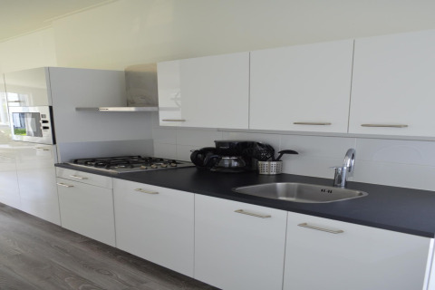 Cucina moderna del lodge “Biebosch” Sunshower nei Paesi Bassi con mobili bianchi e piano nero.