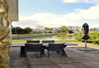 Uitzicht vanaf het terras bij Biebosch-lodge in Nederland met tuinset aan het water en vijver.