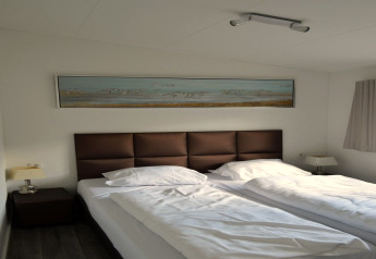 Moderne tweepersoonskamer met bruin hoofdbord en kunst aan de muur bij Biebosch Sunshower in Nederland.