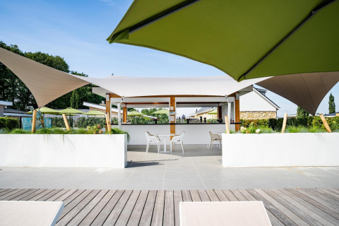 Terrazza esterna presso il Biebosch Sunshower lodge nei Paesi Bassi con ombrelloni e sedute moderne.