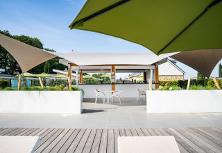 Terrazza esterna presso il Biebosch Sunshower lodge nei Paesi Bassi con ombrelloni e sedute moderne.
