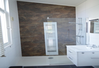 Bagno moderno con sunshower, divisorio in vetro e lavabo bianco presso il lodge «Biebosch» nei Paesi Bassi.