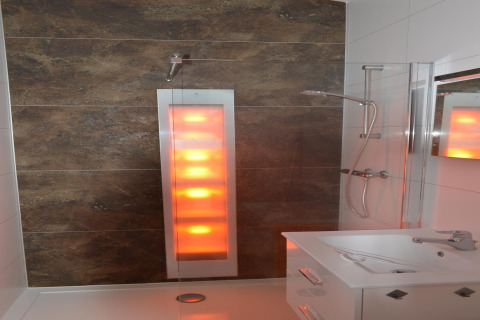 Bagno moderno con doccia solare e pannello luminoso in un lodge olandese, visto dal lato del lavabo.