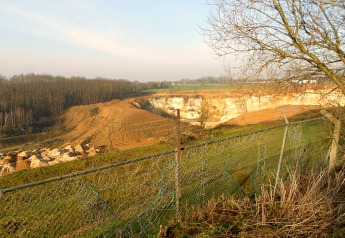 Uitzicht op kaal landschap met aardverschuiving, groen hek en boom bij Biebosch Sunshower in Nederland.