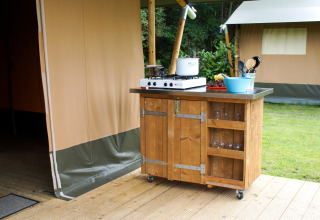 Houten buitenkeuken op wielen met gasfornuis en keukengerei bij een safari tent op Camping Gorishoek.