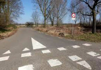 Kruispunt bij Lodge Biebosch in Nederland met wegmarkeringen en een snelheidsbord in de zon.