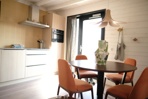 Moderne keuken en eetruimte in Resort Gulpen 3 in Nederland met oranje stoelen en houten wand.