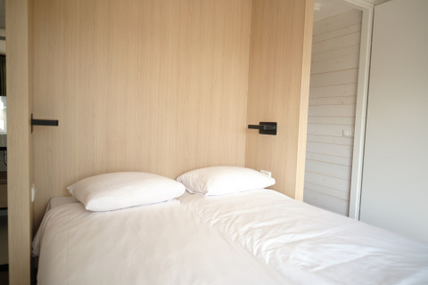 Modern bed met wit linnengoed en kussens in een lichte kamer bij Resort Gulpen 3 in Nederland.