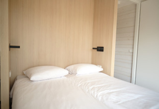 Modern bed met wit linnengoed en kussens in een lichte kamer bij Resort Gulpen 3 in Nederland.