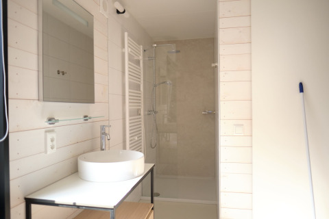 Moderne badkamer in Resort Gulpen 3 in Nederland met douche, witte wasbak en spiegel.