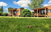 Twee kleine houten huisjes met veranda op groen gras onder blauwe lucht bij Tiny House in Nederland.