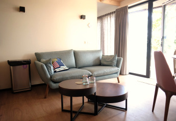 Moderne woonkamer in Resort Gulpen 2, Nederland, met bank, salontafels en glazen schuifdeuren.