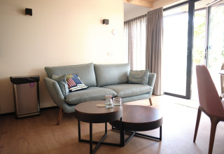 Modern living room in Resort Gulpen 2, Netherlands, featuring a sofa, table, and bright glass doors.