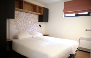 Moderne slaapkamer in Resort Gulpen 2, Nederland, met tweepersoonsbed, wanddecoratie en open kast.