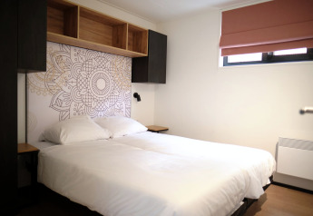 Moderne slaapkamer in Resort Gulpen 2, Nederland, met tweepersoonsbed, wanddecoratie en open kast.