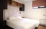Dormitorio moderno en el Resort Gulpen 2, Países Bajos, con cama doble, arte mural y estantería abierta.