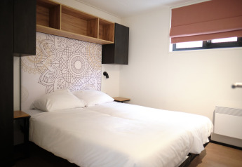 Dormitorio moderno en el Resort Gulpen 2, Países Bajos, con cama doble, arte mural y estantería abierta.