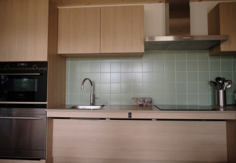 Cocina moderna con muebles de madera, azulejos verdes, horno y fregadero en Resort Gulpen 2, Países Bajos.