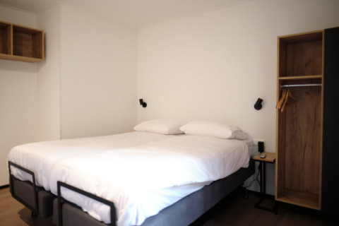 Modern lodge room at Resort Gulpen 2 in the Netherlands, featuring a double bed and minimalistic decor.