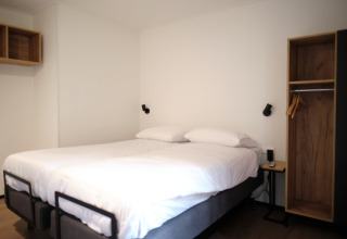 Modern lodge room at Resort Gulpen 2 in the Netherlands, featuring a double bed and minimalistic decor.