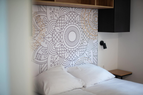 Modern bed with white bedding and artistic headboard at Resort Gulpen 2 in the Netherlands.