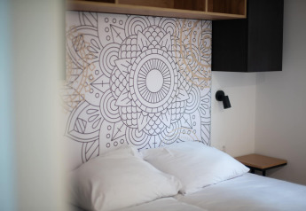 Cama moderna con sábanas blancas y cabecero artístico en Resort Gulpen 2 en los Países Bajos.