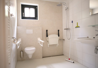 Baño accesible en Resort «Gulpen 2» en los Países Bajos con barras de apoyo, ducha y sanitario