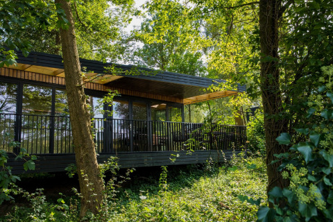 Modern lodge at Resort Gulpen 2 in the Netherlands, surrounded by lush forest and green trees in summer.
