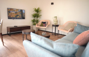 Moderne stue i Resort Gulpen 1 med sofa, stole, planter og vægmonteret tv, Nederlandene.
