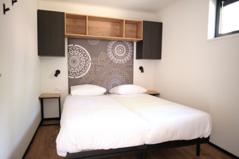 Habitación de lodge moderna con dos camas individuales y estanterías de madera en Resort Gulpen 1, Países Bajos.