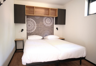 Habitación de lodge moderna con dos camas individuales y estanterías de madera en Resort Gulpen 1, Países Bajos.