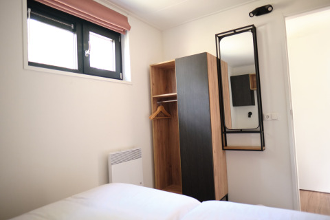 Dormitorio moderno en el Resort Gulpen 1, Países Bajos, con armario, espejo y dos ventanas.