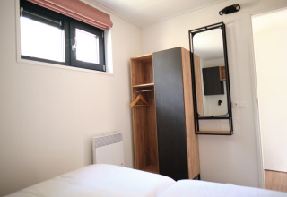 Dormitorio moderno en el Resort Gulpen 1, Países Bajos, con armario, espejo y dos ventanas.