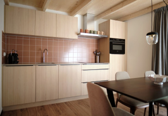 Cuisine moderne avec armoires en bois clair, crédence brune et coin repas au Resort Gulpen 6, Pays-Bas.