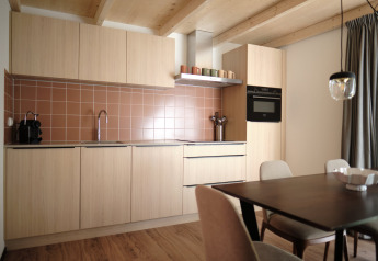Cocina moderna con gabinetes de madera clara, azulejos marrones y comedor en Resort Gulpen 6, Países Bajos.