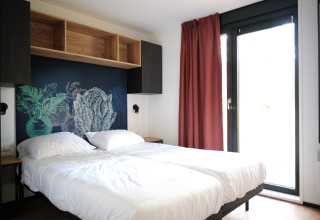 Moderne slaapkamer in Resort Gulpen 6, Nederland, met dubbel bed, muurkunst en grote ramen.