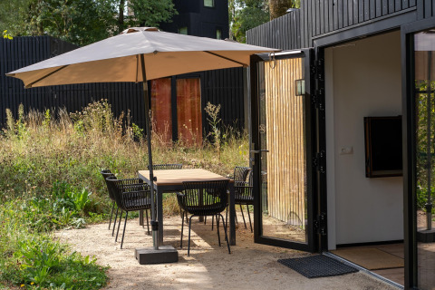 Buitenruimte met eetset en parasol aan Resort Gulpen 6 in Nederland, tafel en stoelen zichtbaar.