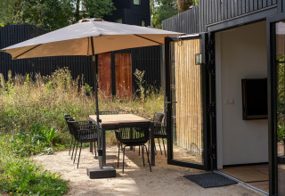 Buitenruimte met eetset en parasol aan Resort Gulpen 6 in Nederland, tafel en stoelen zichtbaar.