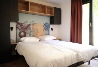 Moderne lodgekamer in Resort Gulpen 6 in Nederland met twee eenpersoonsbedden en een muurschildering.
