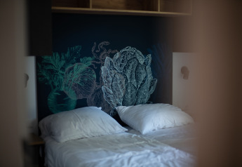 Dos camas individuales con almohadas blancas y fondo de vegetales en Resort Gulpen 6, Países Bajos.