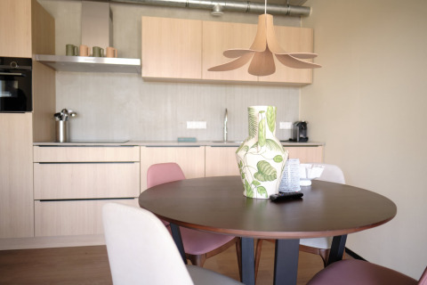 Moderne keuken en eethoek in Resort Gulpen 5, Nederland, met ronde tafel en decoratieve vaas.